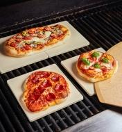 Homemade pizzas cooking on barbecue pizza stones in a barbecue