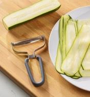 Extra-wide Y-peeler on a cutting board next to a plate of zucchini noodles