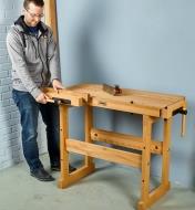 A man securing a block of wood in the front vise of the Sjöbergs apartment workbench