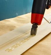 Installing trim using a double-flow nozzle on a FastenMaster Pro Hot-Melt Gun to glue it in place