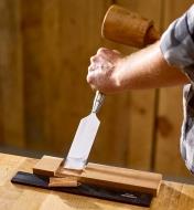 A woodworker drives a 1 1/2" Narex Richter chisel with a wooden mallet to trim the bottom of a large dado