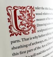 A detail view of a foliate initial on a page from the deluxe edition of Roubo On Furniture
