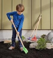 A child digs in a garden using the spade from the children’s garden tools set