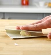 Peeling a garlic clove on a countertop using the garlic peeling mat