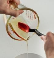 The mini spoon-spatula used to scrape liquid honey from a measuring cup