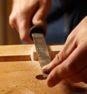 Filing a wood piece in a vise with a rasp