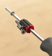 A magnetized screwdriver holds a screw, with others held to a magnetizer/demagnetizer on its shank