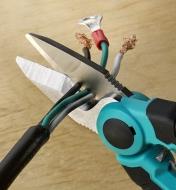 A close view of the electrician scissors cutting three-strand conductor cable