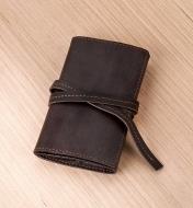 A leather cord wallet on a tabletop, cinched closed with its leather tie