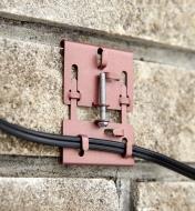 Brick clamp supporting wires horizontally on a brick wall