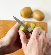 Peeling a kiwi fruit with the serrated paring knife