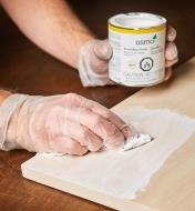 Using a cloth to apply Osmo white wood wax to a wood surface