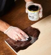 Using a cloth to apply Osmo ebony wood wax to a wood surface