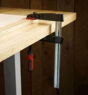 A Bessey 5 1/2" medium-duty FA clamp clamping a piece of wood to a workbench