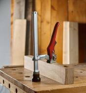 A Bessey hold-down clamp with a lever handle clamping a block of wood to a workbench