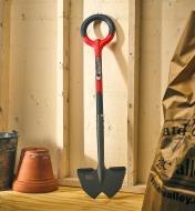 A Radius root cutter lawn edger leaning against the wall of a garden shed.