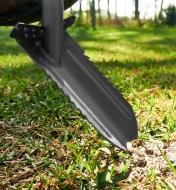 A close view of the root-cutter trenching spade’s blade penetrating the soil