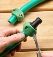 Attaching the hose mender to a section of garden hose using a screwdriver