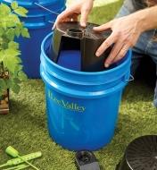 Lowering the reservoir of the GroBucket self-watering insert into a bucket