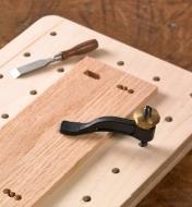 A small workpiece is secured vertically with the miniature hold-down, ready to be mortised with the miniature chisel in the background