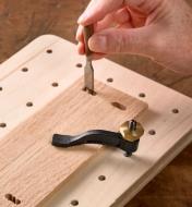 A small workpiece is secured vertically with the miniature hold-down while a mortise is being chiselled with a miniature chisel