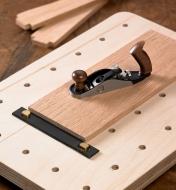 A miniature planing stop is used in combination with a pair of miniature surface dogs for planing a thin workpiece with a miniature bench plane