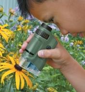 A child uses the Pocket Microscope to look at a flower