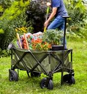Plants, along with tools and bags of soil, carried in a folding cart to a garden bed for planting