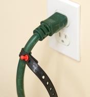 An extension cord plugged into a wall with a Wrap-N-Strap attached to it