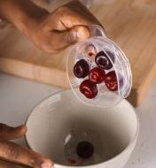 Emptying pitted cherries from the tray of the six-cherry pitter