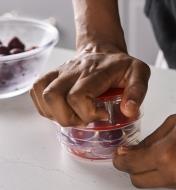 Pressing on the arm of the six-cherry pitter to push pits out of cherries