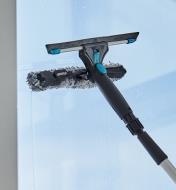 Using the microfiber scrubber of the dual-head window-washing set to clean a window