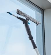 Using the rubber squeegee of the dual-head window-washing set to wipe a window dry