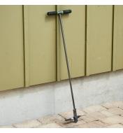 A compost aerating tool leaning against a wall