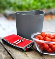 A small hip-trug removed from its neoprene holster, next to a small harvest of grape tomatoes