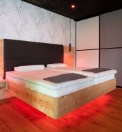 A double bed with a red glow under the bed frame
