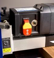An orange toggle switch with a yellow tab built into it on the front of the Rikon 13" helical planer