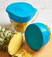 Large seal caps covering contents in a measuring cup and the remainder of a pineapple.