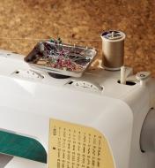 A mini magnetic parts tray holding pins sits atop a sewing machine