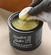 Dipping a cloth into a container of Walrus Oil furniture butter