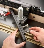 Tightening the knobs on a Mite-R-Slide II miter fence to set it flush to the router fence