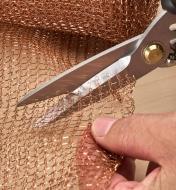 Using the shears to cut copper blocker mesh used to repel slugs in the garden