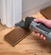 Undercutting a piece of trim with a fan blade on a multi-tool to accommodate a flooring installation
