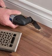Using a multi-tool with a square-tipped blade to cut a hole for a heat register into flooring