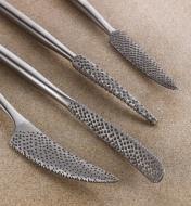 A close view of four stainless-steel riffler tips showing the varied shapes and hand-stitched teeth