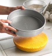 After removing a cake, a baker shows that nothing stuck to the 9" round cake pan’s silicone coating