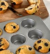 Three blueberry muffins neatly removed from the non-stick surface of a muffin pan made by USA Pan