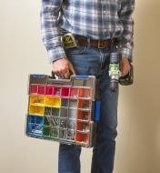 A man carries a drill and an Allit Pro 18-compartment case containing drill bits and hardware items