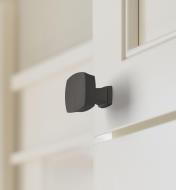 One matte black Stature square knob mounted to a cupboard door
