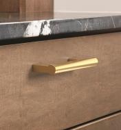 A champagne bronze Versa handle mounted to a drawer